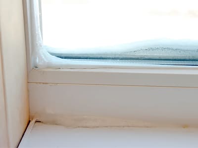 Промерзло пластиковое окно зимой
